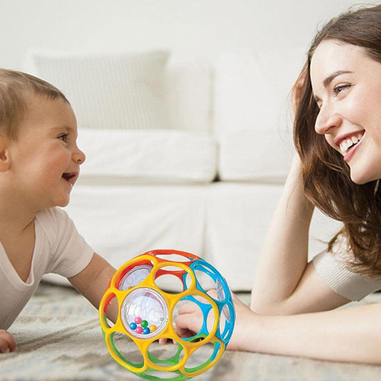 Bébé tenant la balle sensorielle et la mordillant pour soulager ses gencives