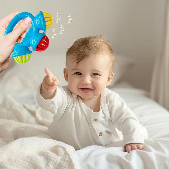 Hochet Clochette Douceur posé dans un berceau avec des accessoires pour bébé