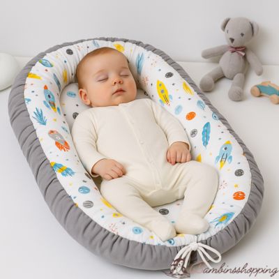 bébé dort dans réducteur de lit aux motifs fusées