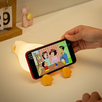 Veilleuse Lazy Duck utilisée comme support pour un téléphone, ajoutant une touche ludique à la chambre