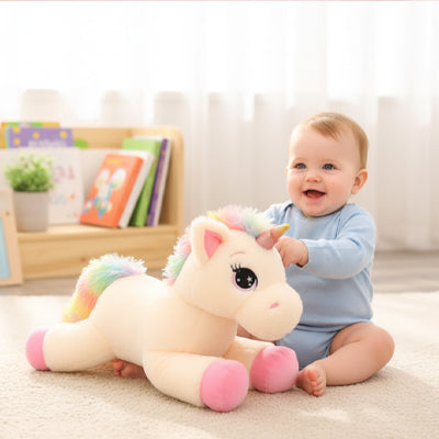 bébé sourit avec peluche licorne rose