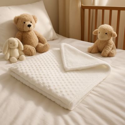 couverture bébé blanche sur lit entourée de peluches
