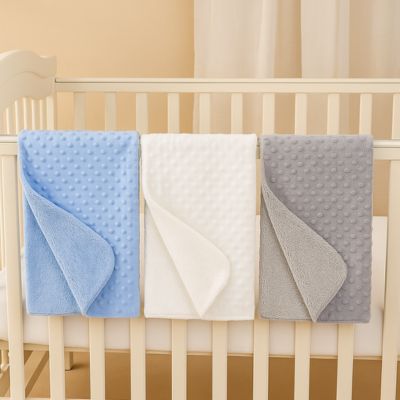 couverture bébé bleu blanc gris suspendue à un lit à barreaux