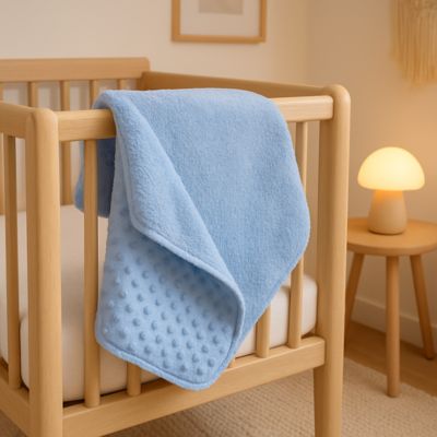 couverture bébé bleue posée sur lit avec veilleuse