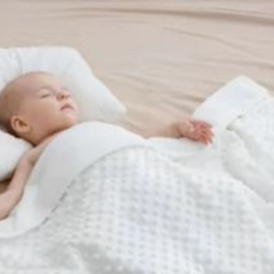 Bébé endormi sous une couverture bébé blanche moelleuse