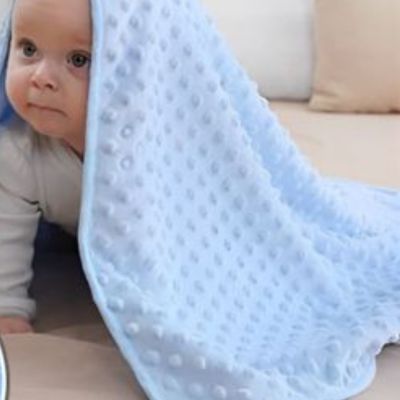 Bébé qui rampe avec une couverture bébé bleue à pois