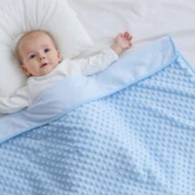 Bébé réveillé sous une couverture bébé bleue toute douce