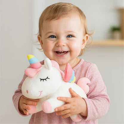 bébé sourit avec licorne peluche blanche