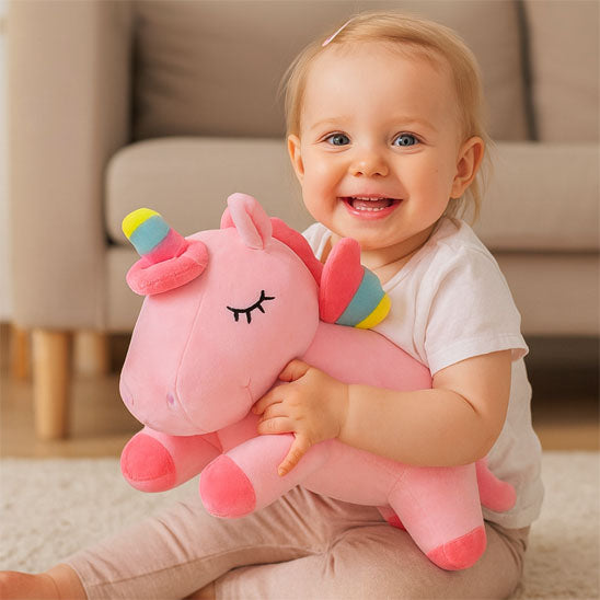 licorne peluche rose dans les bras bébé