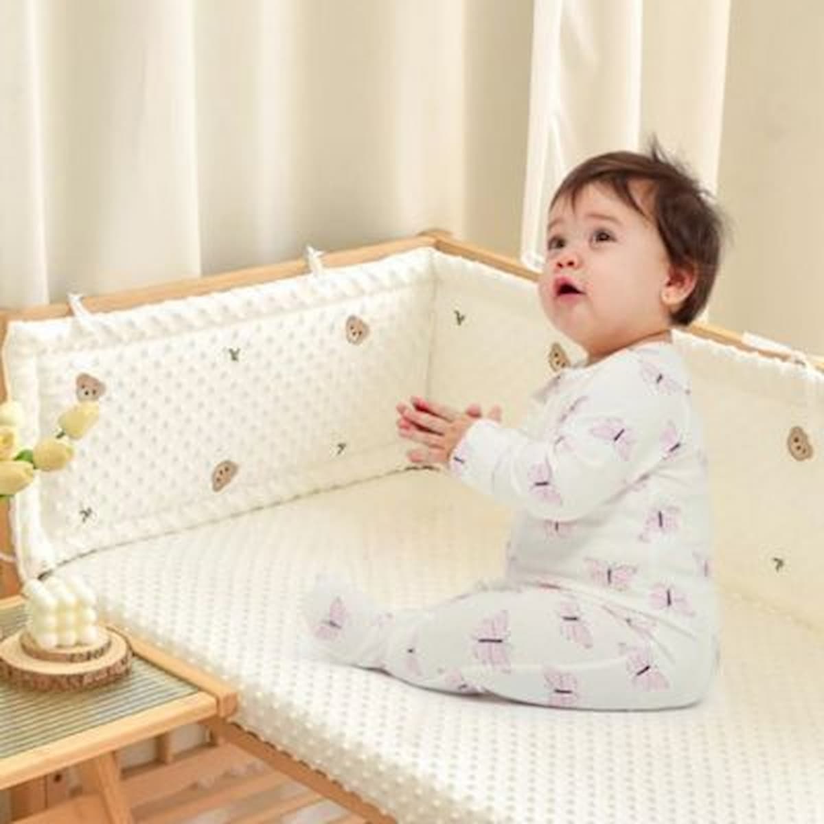 Bébé assis dans son lit avec tour de lit bébé
