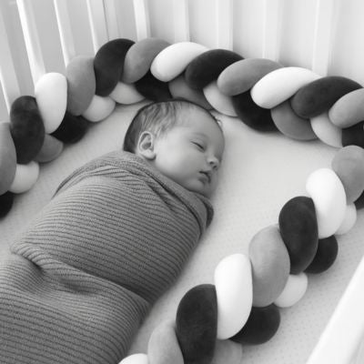 Tour de lit tressé avec nouveau-né qui dort