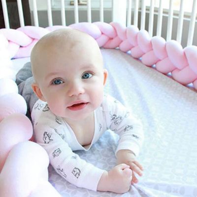 Bébé allongé dans son lit avec un tour de lit tressé rose pastel