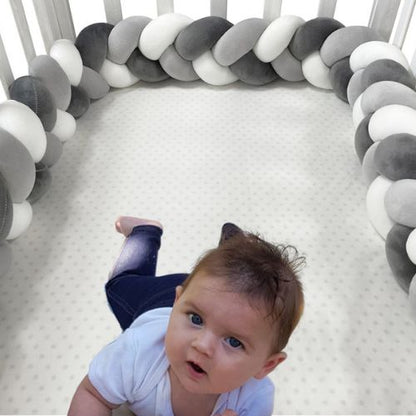 Bébé allongé dans lit sécurisé par une tresse de lit bébé grise et blanche