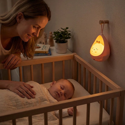 Veilleuse bébé rose accrochée près du lit à barreaux