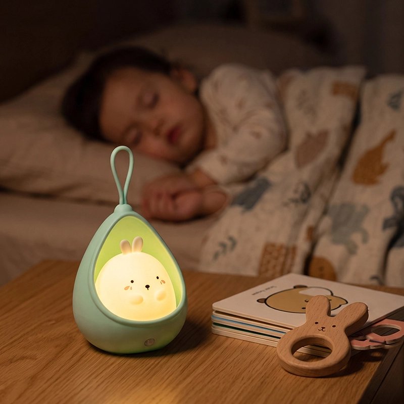 Veilleuse lapin turquoise près d'un enfant endormi